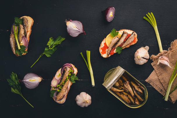A set of sandwiches with sprats, and caviar, onion and parsley, on a wooden background. Top view. Copy space. - Fotoğraf, Görsel