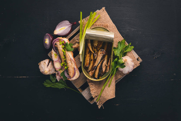 Sandwich with sprats, onions and parsley, on a wooden background. Top view. Copy space. - Foto, Bild
