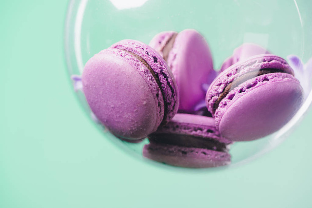 close-up shot of pink macarons in glass ball on turquoise background - Фото, зображення