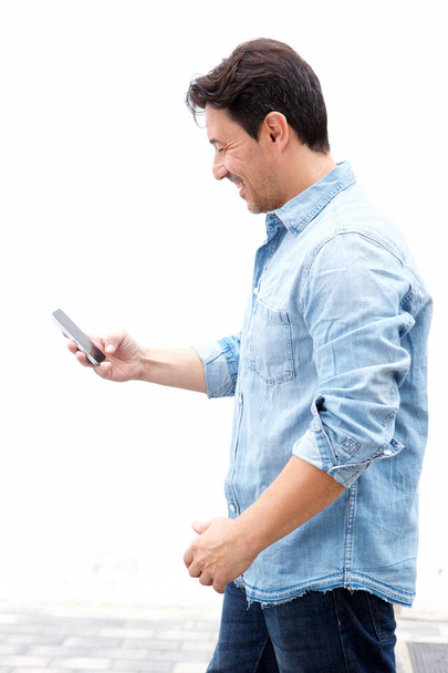 Portrait latéral d'un homme d'âge moyen lisant un message texte sur son téléphone portable
 - Photo, image
