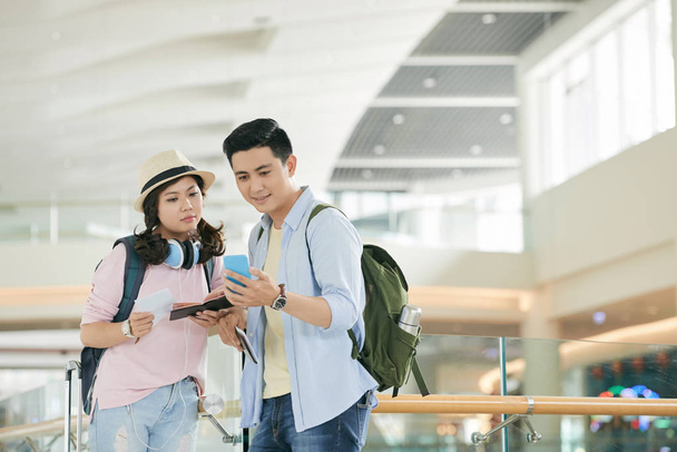 Mladý vietnamský pár kontrolní plán na smartphone v terminálu letiště - Fotografie, Obrázek