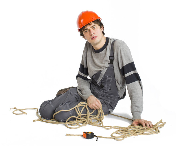 A young worker in grey uniform tied up with rope on white isolated background. - Photo, Image