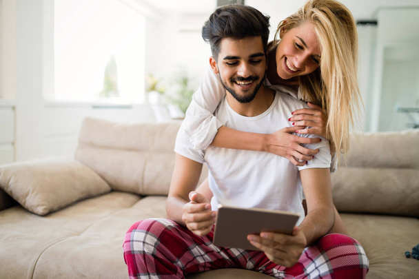 Verliebtes glückliches Paar mit Tablet im Pyjama zu Hause - Foto, Bild