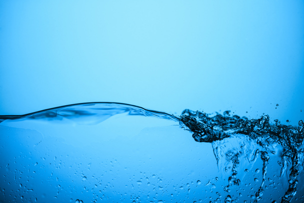 flowing water texture with bubbles and drops, isolated on blue - Photo, Image