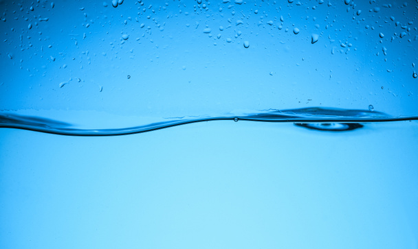 clear flowing water texture with drops, isolated on blue - Foto, Imagem