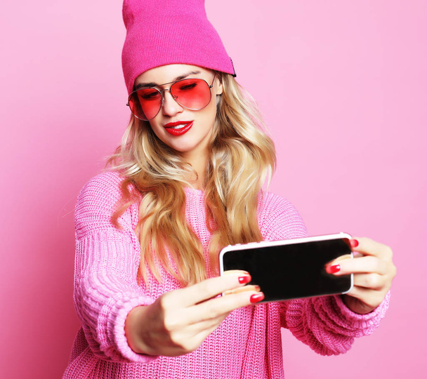 Fashion girl  taking photo makes self portrait on smartphone wea - Valokuva, kuva