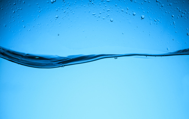 flowing water texture with drops, isolated on blue - Photo, Image