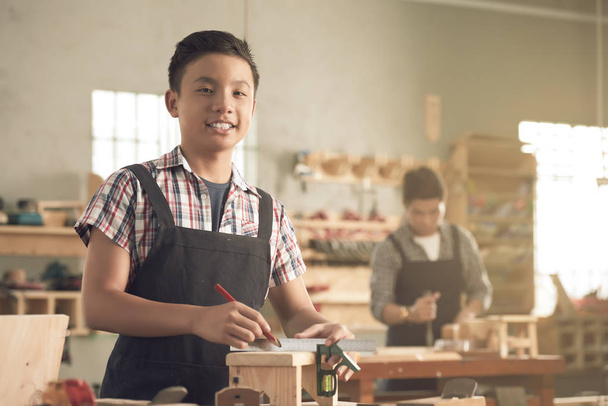 Счастливый мальчишка работает в столярной мастерской со своим отцом
 - Фото, изображение