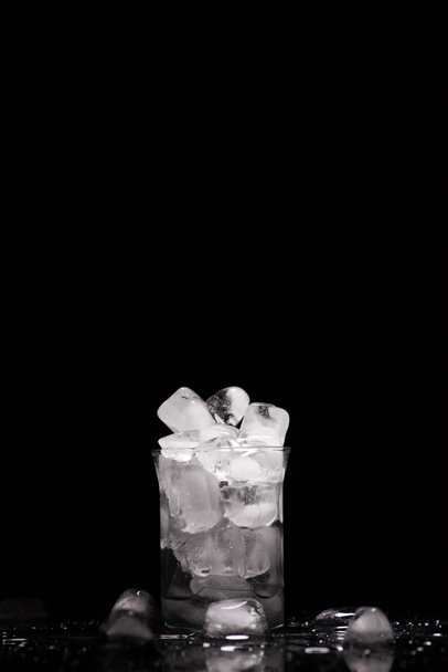 λιώσιμο των πάγων σε κύβους int γυαλί, σε μαύρο χρώμα με σταγόνες - Φωτογραφία, εικόνα