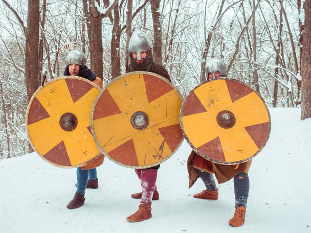Egy csoport fegyveres középkori harcosok őrzik, pajzsok, kardok, spears a téli erdő - Fotó, kép