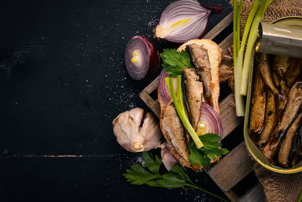 Sandwich with sprats, onions and parsley, on a wooden background. Top view. Copy space. - Foto, Imagen