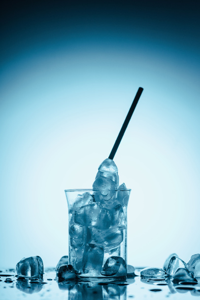 smeltende ijsblokjes in het glas met rietje, op wit  - Foto, afbeelding