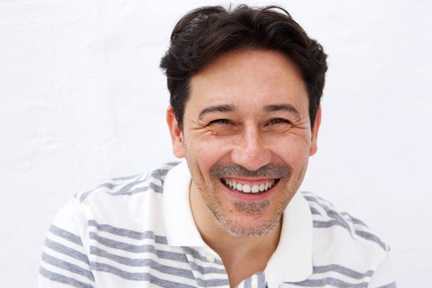 Close-up van portret van vrolijke volwassen man die lacht tegen witte achtergrond - Foto, afbeelding