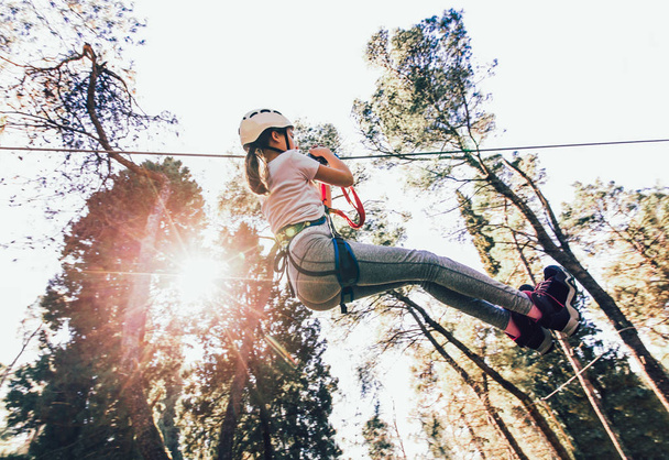 Bonne écolière profitant d'une activité dans un parc d'aventure d'escalade par une journée ensoleillée
 - Photo, image