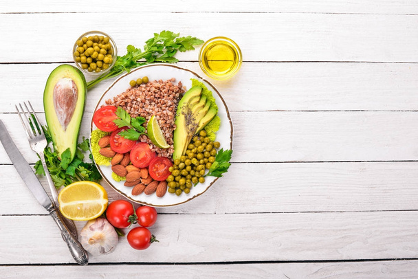 Healthy food. Buckwheat, cherry tomatoes, avocados, almonds and green peas. On a wooden background. Top view. Free space for your text. - Фото, изображение