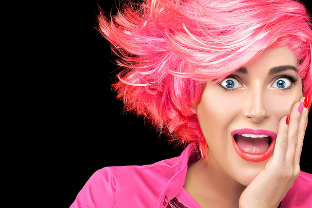 Έκπληκτος όμορφη νεαρή γυναίκα με ντεγκραντέ ροζ μαλλιά, ανοίξτε το στόμα με το χέρι στο μάγουλο και χαρούμενος/η ή έκπληκτος έκφραση. Μοντέρνα, βαμμένα μαλλιά. - Φωτογραφία, εικόνα