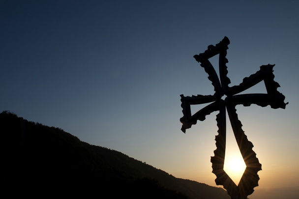 Croce cristiana in metallo al tramonto con sfondo di montagna
 - Foto, immagini