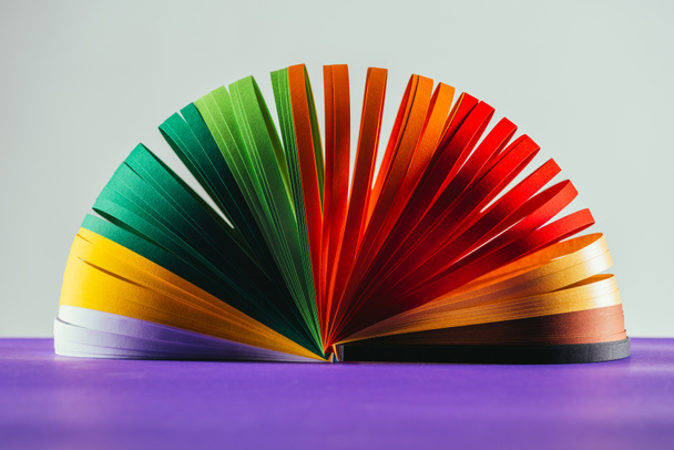 barevné quilling papíru křivky na fialovou povrchu na bílém - Fotografie, Obrázek