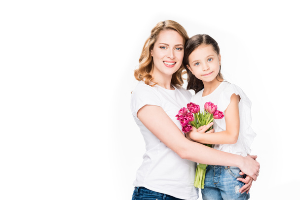 portréja vidám anya és lánya kis csokor virágot elszigetelt fehér, anyák napi koncepció - Fotó, kép