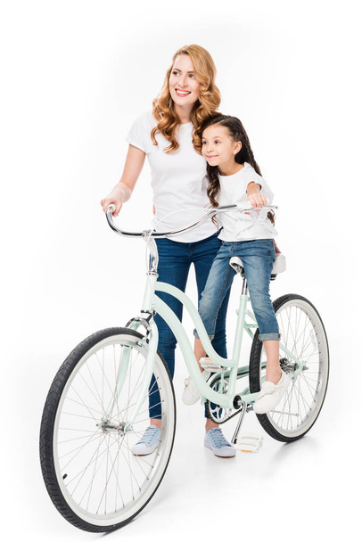 smiling woman and daughter on retro bicycle isolated on white - Fotó, kép