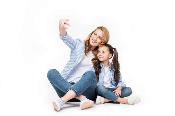 feliz madre e hija tomando selfie en el teléfono inteligente juntos aislados en blanco
 - Foto, imagen