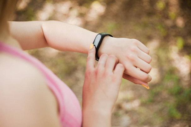 Young sporty girl looking at her fitness tracker - Photo, Image