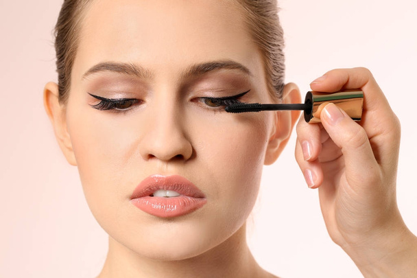 Professional visage artist applying makeup on woman's face on light background - Фото, изображение