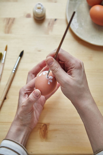 close-up of female hands painting eggs with various white floral patterns for Easter holiday   - Фото, изображение
