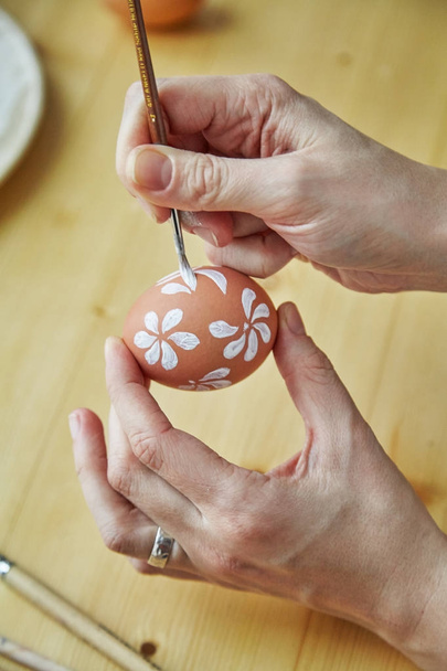 close-up of female hands painting eggs with various white floral patterns for Easter holiday   - Foto, Imagem