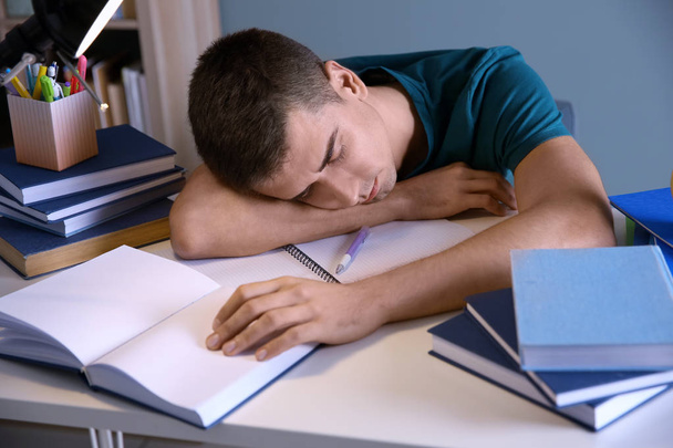 Tired student sleeping at his desk indoors. Preparing for exam - Foto, imagen