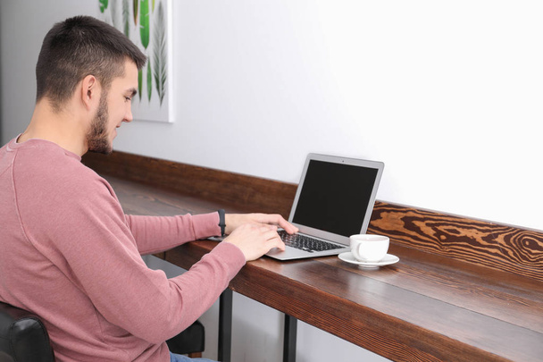Молодой человек с современным ноутбуком в кафе
 - Фото, изображение