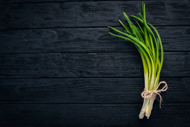 Fresh green onion on a wooden background. Top view. Free space for your text. - Фото, изображение