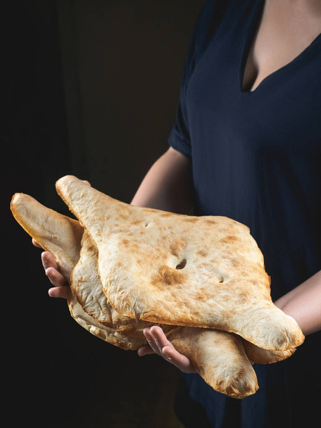частковий вид людини, що тримає смачні традиційні грузинські плоскі хліби
 - Фото, зображення