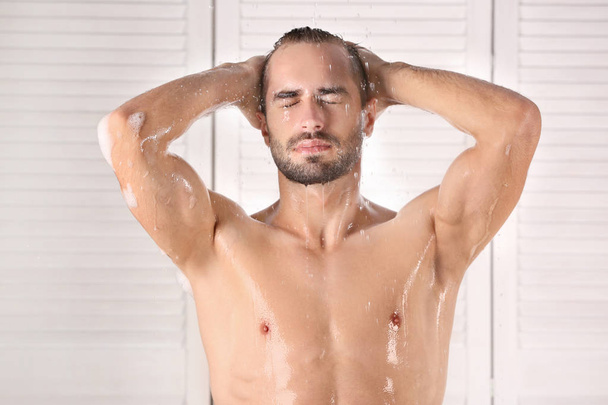Young handsome man taking shower in bathroom - Fotó, kép