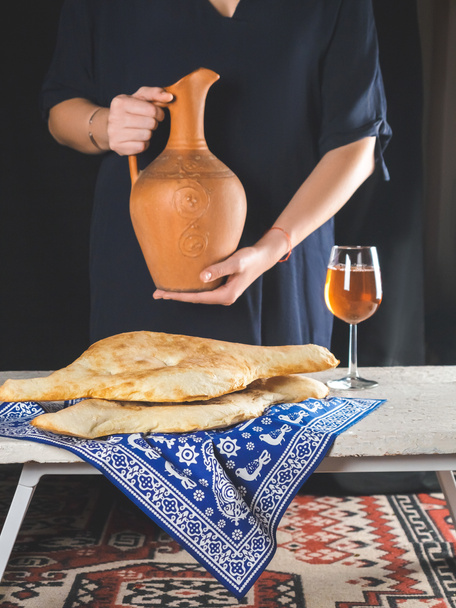 delicious georgian lavash with glass of beverage and person holding clay jug behind - Photo, Image
