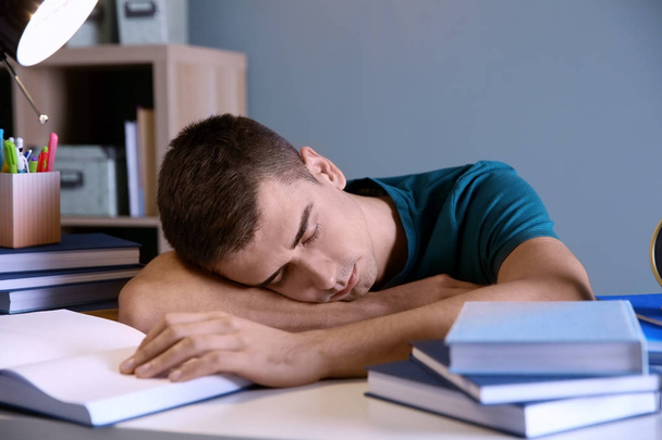 Tired student sleeping at his desk indoors. Preparing for exam - Photo, image