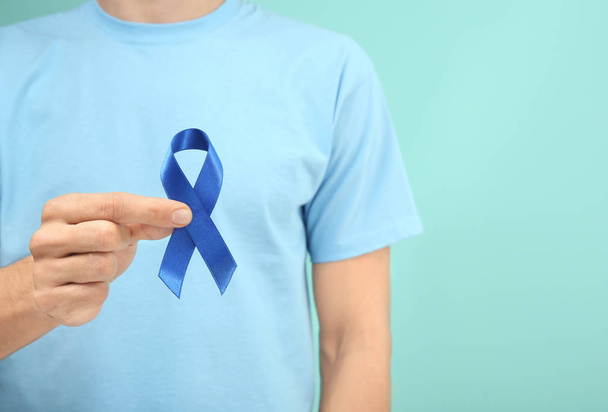 Man holding blue ribbon on color background, closeup. Prostate cancer awareness - Φωτογραφία, εικόνα
