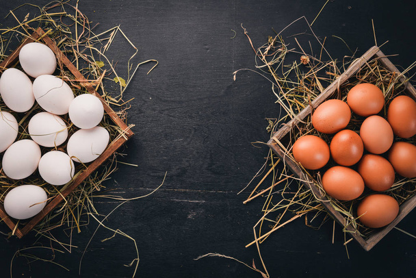 Chicken raw eggs in a wooden basket. On a wooden background. Top view. Copy space. - Foto, afbeelding