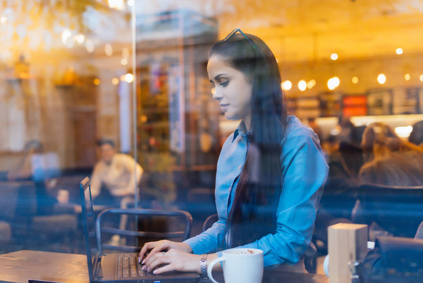 жінка сидить за столом, і це друкує за комп'ютером і п'є каву
 - Фото, зображення