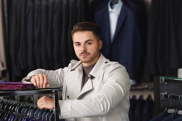 Young man in stylish coat at menswear store - Foto, imagen