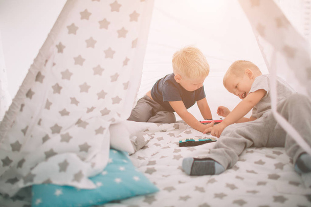 Kids brothers are laying on the floor. Boys are playing in home with toy cars at home in the morning. Casual lifestyle in bedroom. - Фото, изображение