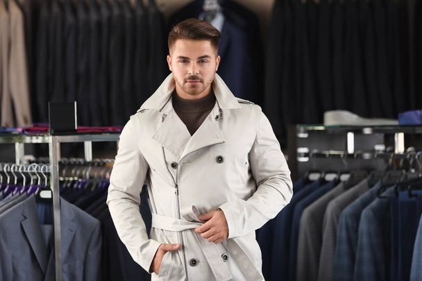 Young man in stylish coat at menswear store - Foto, afbeelding