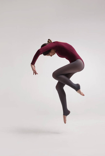 young woman dancer in maroon swimsuit jumping - Foto, immagini