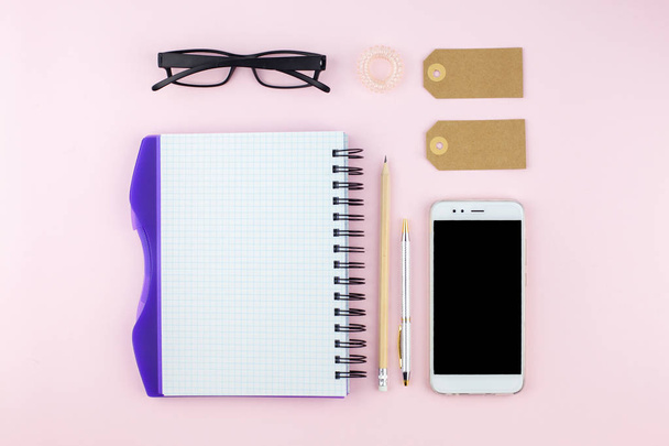 kreative flache Lay-Foto des Arbeitsplatzes Schreibtisch mit Smartphone, Brille, Stift, Bleistift und Notizbuch, minimalen Stil auf rosa Hintergrund. Minimales Geschäftskonzept - Foto, Bild
