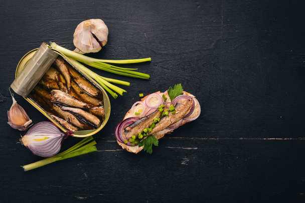 Sandwich with sprats, onions and parsley, on a wooden background. Top view. Copy space. - Foto, imagen