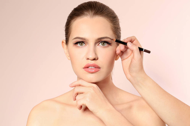Professional visage artist applying makeup on woman's face on light background - Fotó, kép