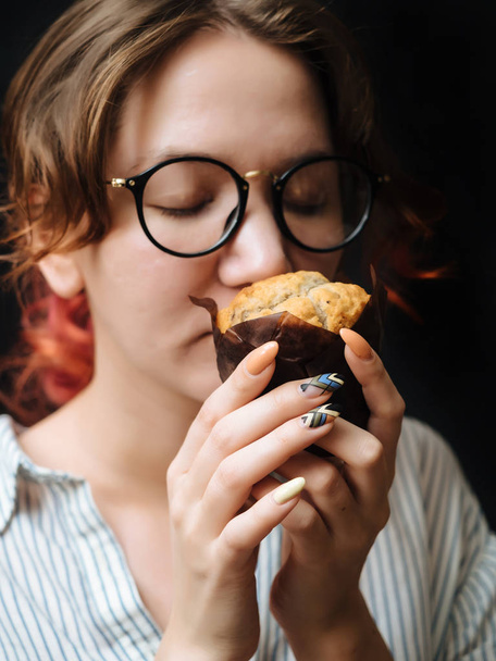 Joven sonrisa chica con muffin en el fondo negro
 - Foto, Imagen
