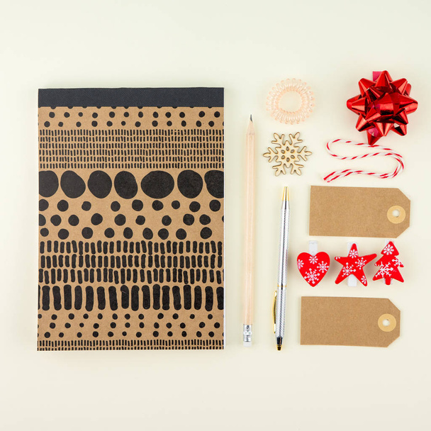 Creative flat lay photo of workspace desk with eyeglasses, pen, pencil and notebook, minimal style on cream background. Minimal Chtistmas shopping concept with tags and christmas decoration - Foto, afbeelding