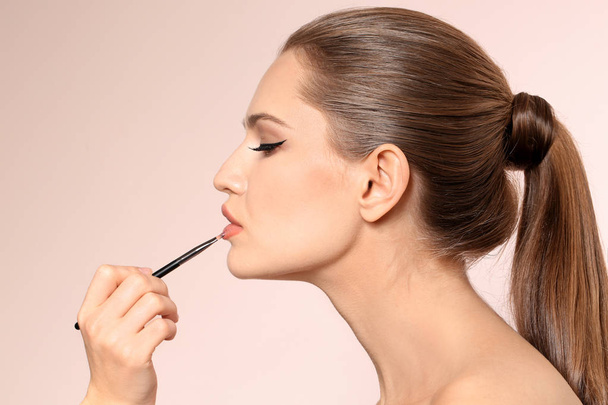 Professional visage artist applying makeup on woman's face on light background - Photo, Image