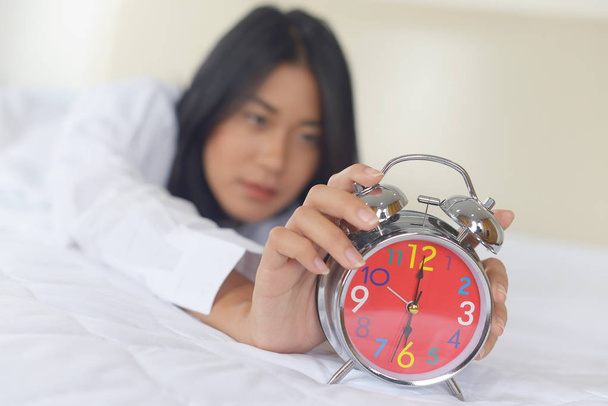 Молода жінка відкладає будильник вранці
 - Фото, зображення